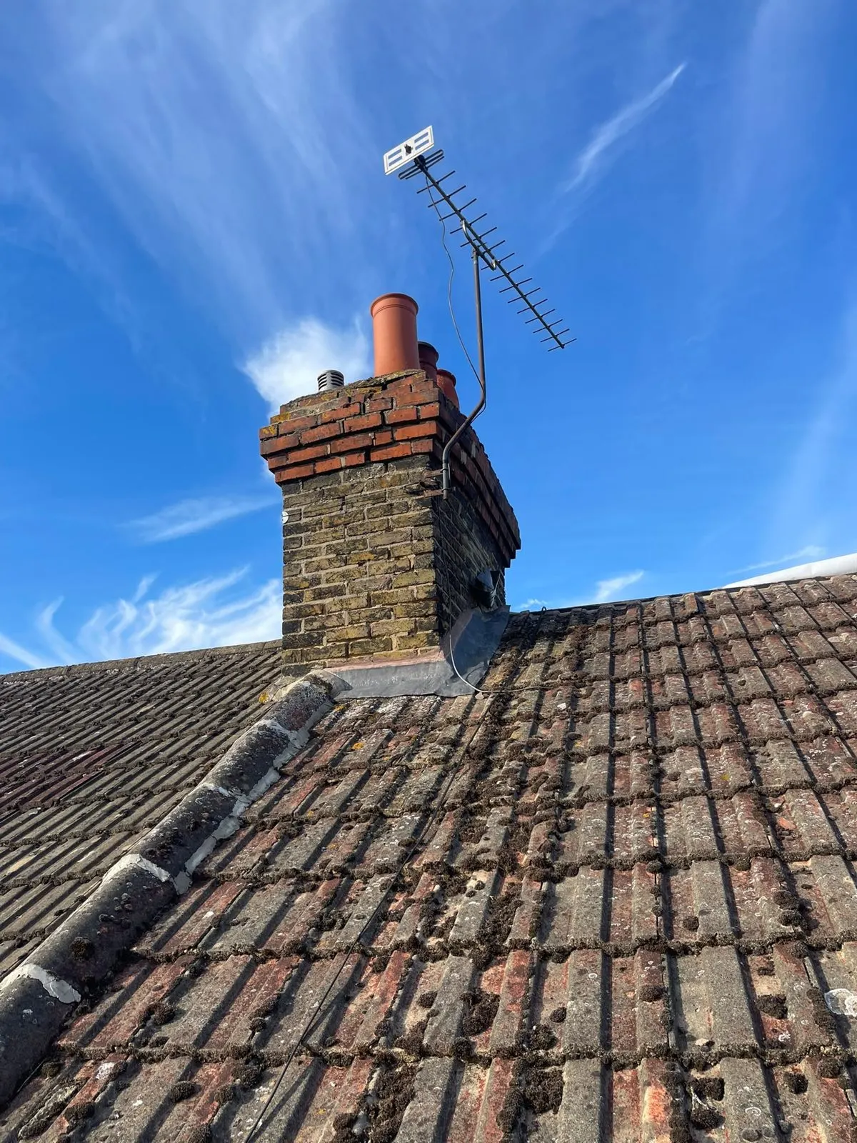 Weathered tiled roof beside a chimney stack