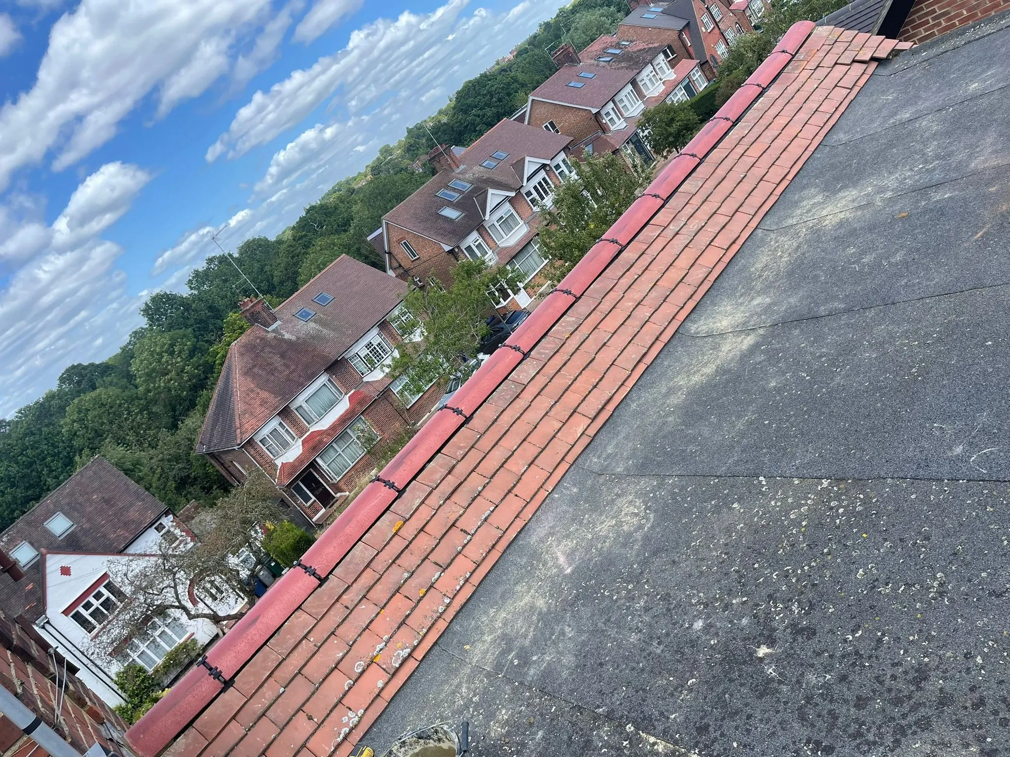 Flat roof edge with red capping above rooftops