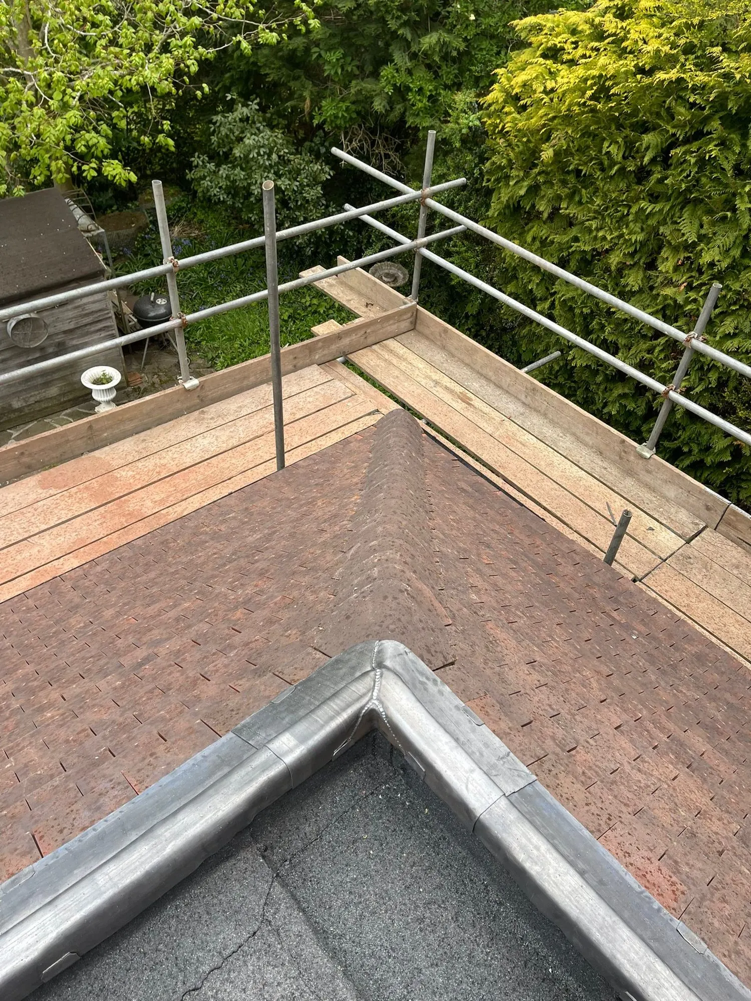 Flat roof upstand beside a clay tiled roof