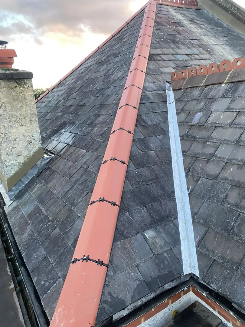 Slate roof with red ridge tiles and a lead valley