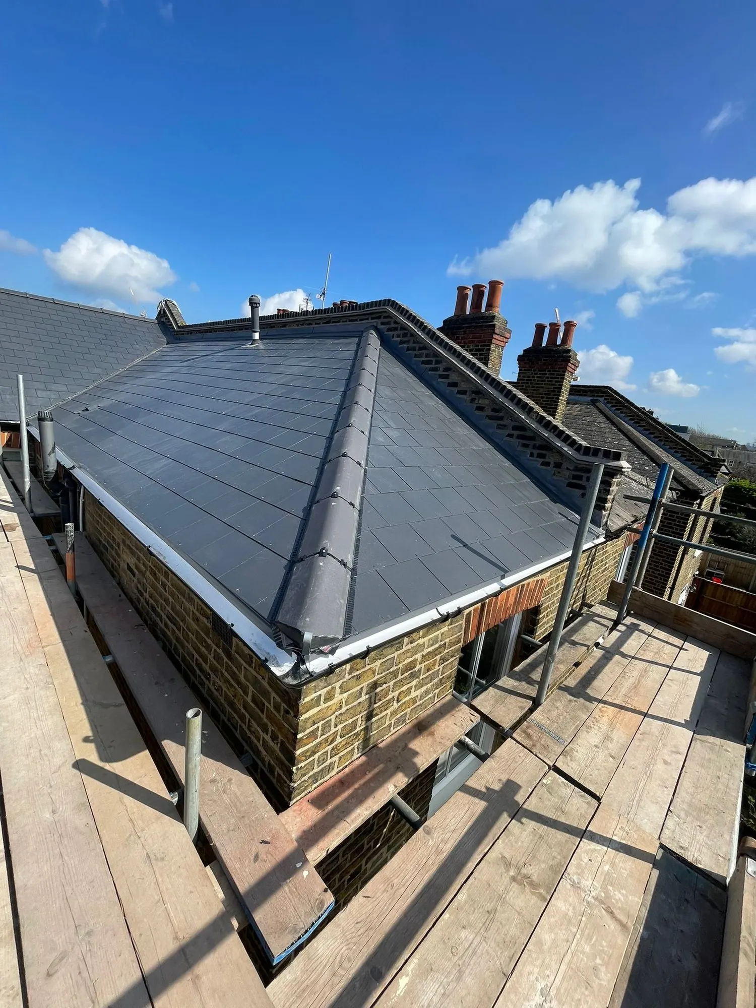 New slate hip roof over a brick bay